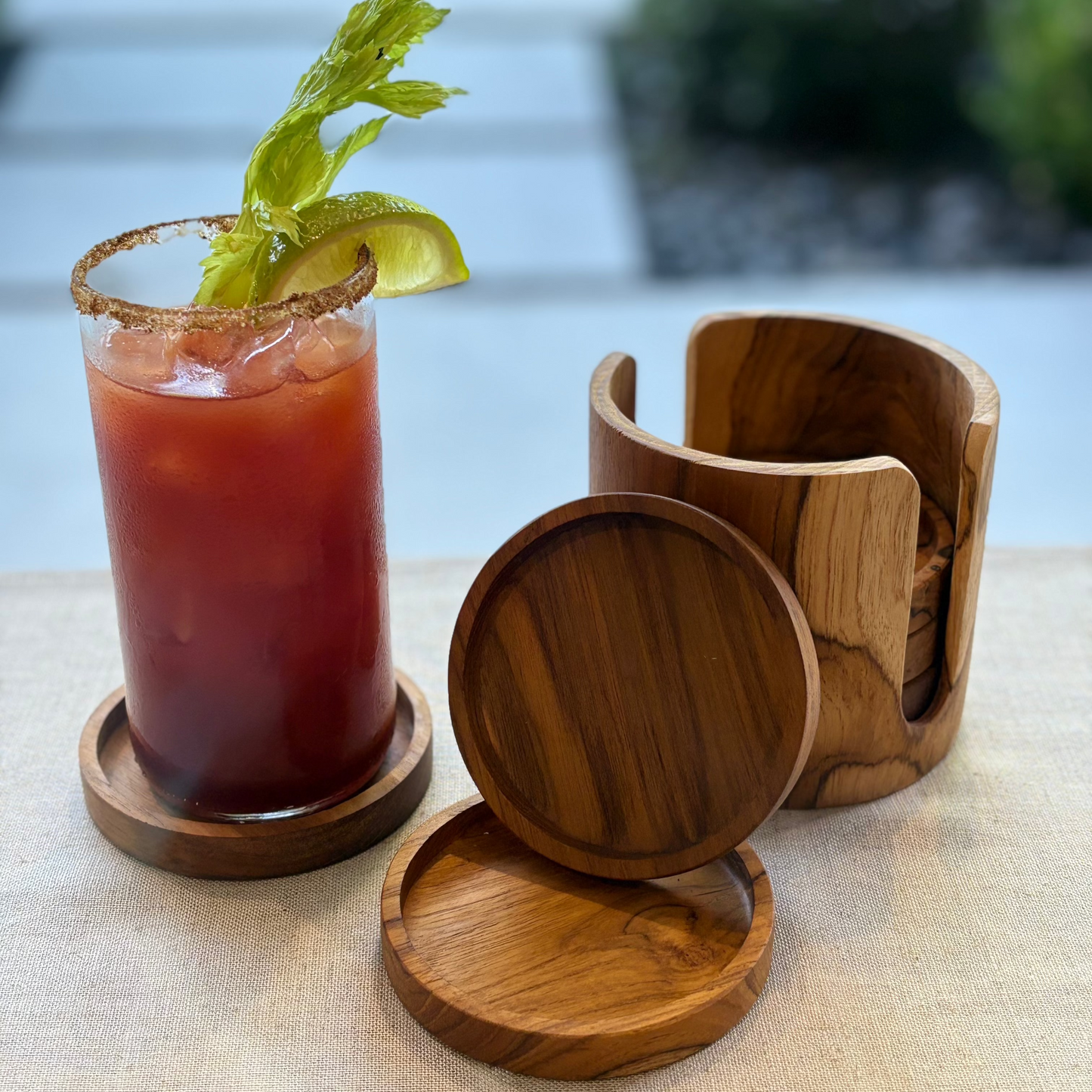 A round teak wooden coaster set with a natural wood grain pattern, shown with a cocktail in an outdoor setting
Coaster: 10cm x 1.5cm
Holder: 12cm x 10.5cm