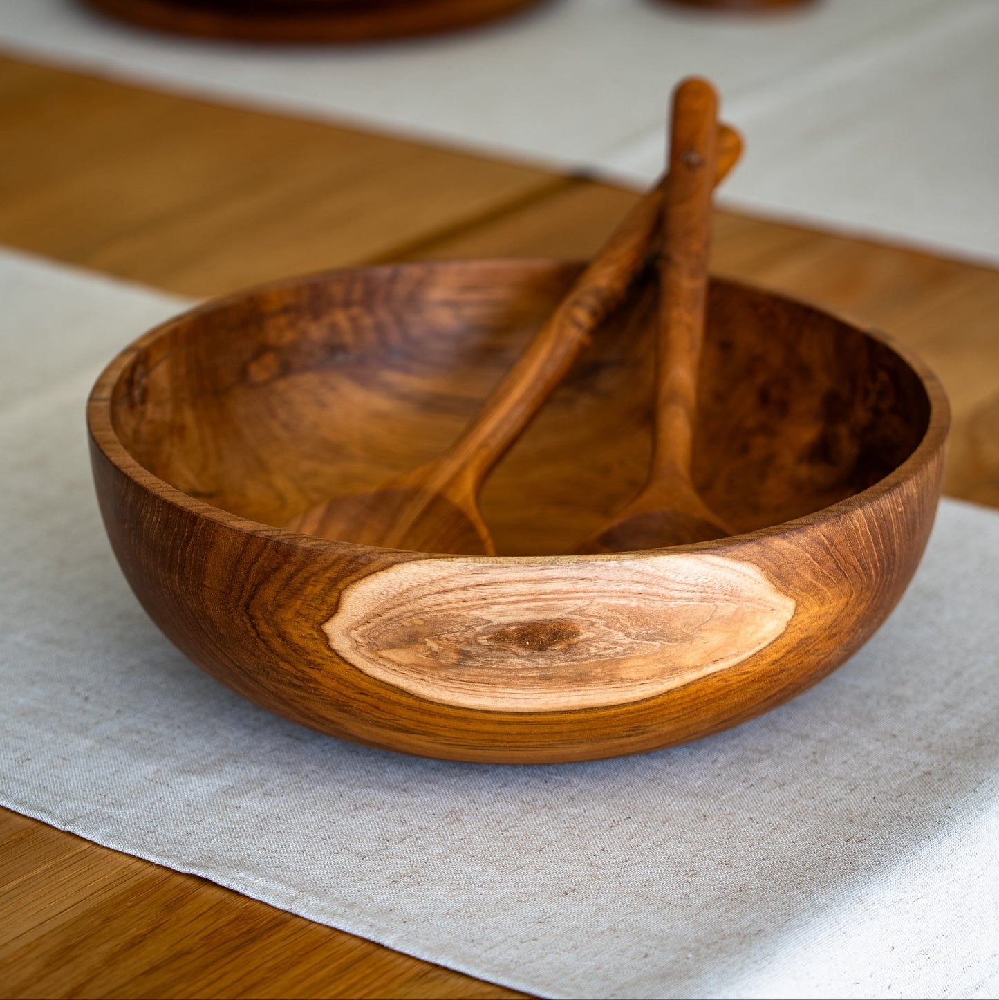 Image of teak salad bowl with a pair of teak salad servers. Durable and high quality, handcrafted from sustainable teak root, which makes every piece a one-of-a-kind.Dimensions 28cm x 9cm x 2cm.