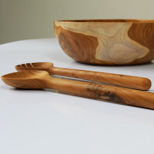 Image of teak salad bowl with a pair of teak salad servers. Durable and high quality, handcrafted from sustainable teak root, which makes every piece a one-of-a-kind.Dimensions 28cm x 9cm x 2cm.