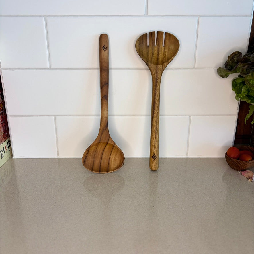 Image of teak salad servers. Durable and high quality, handcrafted from sustainable teak root, which makes every piece a one-of-a-kind. Dimensions 28cm x 9cm x 2cm.
