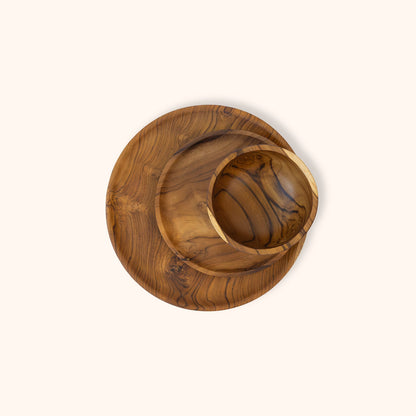 A round wooden bowl with a matching saucer and larger plate, photographed from directly above on a solid off-white background.