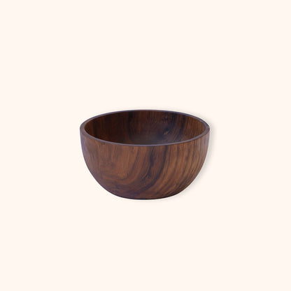 A dark brown teak wooden bowl with a prominent wood grain pattern, photographed against a solid off-white background.