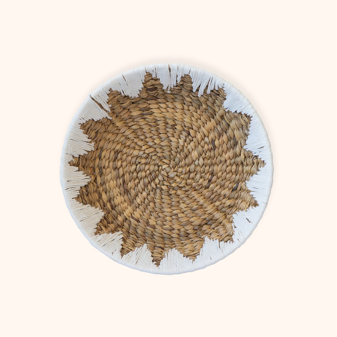 A round water hyacinth woven basket  and a white sewn rim, photographed from above on a plain light beige background.