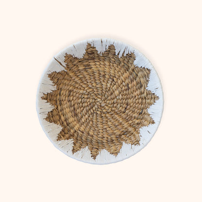 A round water hyacinth woven basket  and a white sewn rim, photographed from above on a plain light beige background.