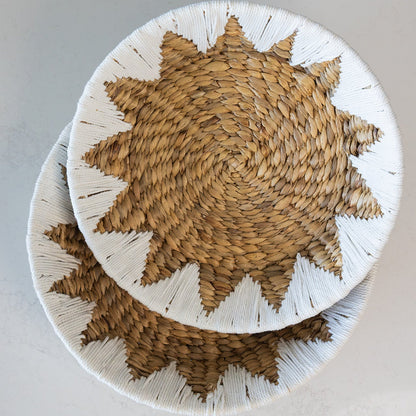 Two round Water_Hyacinth fruit and veggie baskets with a starburst pattern in natural tan and white, stacked on a light gray surface.