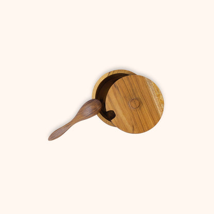 Teak salt keeper with spoon shown on a clean background from overhead angle