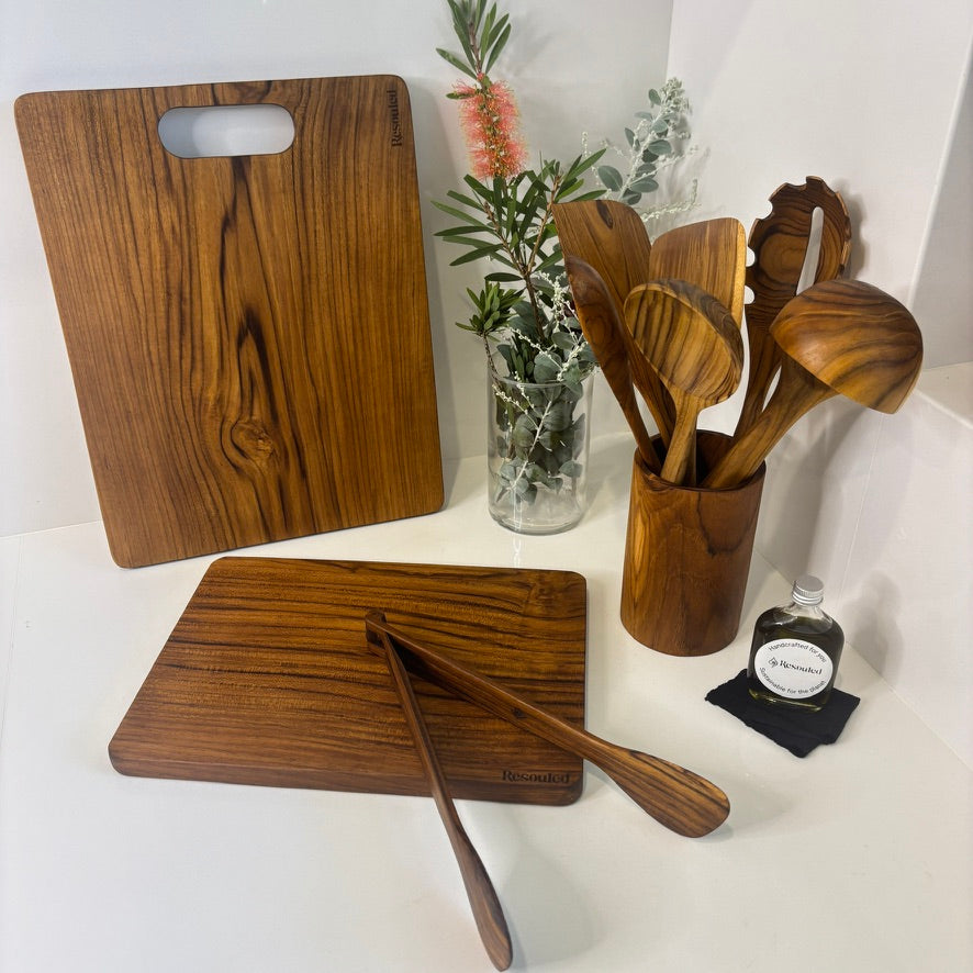 Image showing set of 2 teak chopping boards and teak utensils vs competitor wood fibre board, highlighting plastic-free materials, knife-friendliness, and natural sustainability.