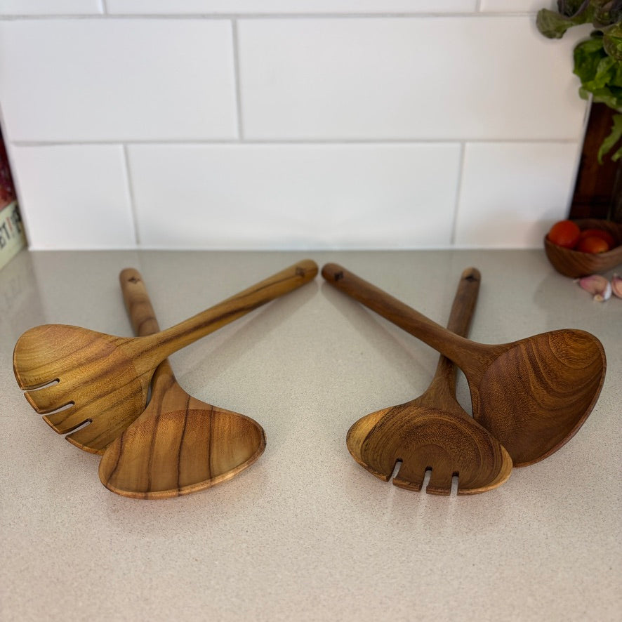 Image of teak salad servers. Durable and high quality, handcrafted from sustainable teak root, which makes every piece a one-of-a-kind. Dimensions 28cm x 9cm x 2cm.